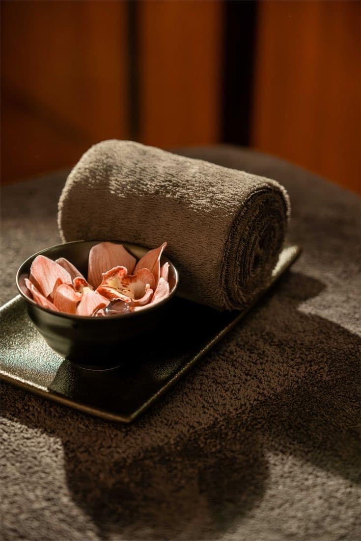A rolled towel and a bowl of flower petals ready for a treatment at D-Urban Lounge